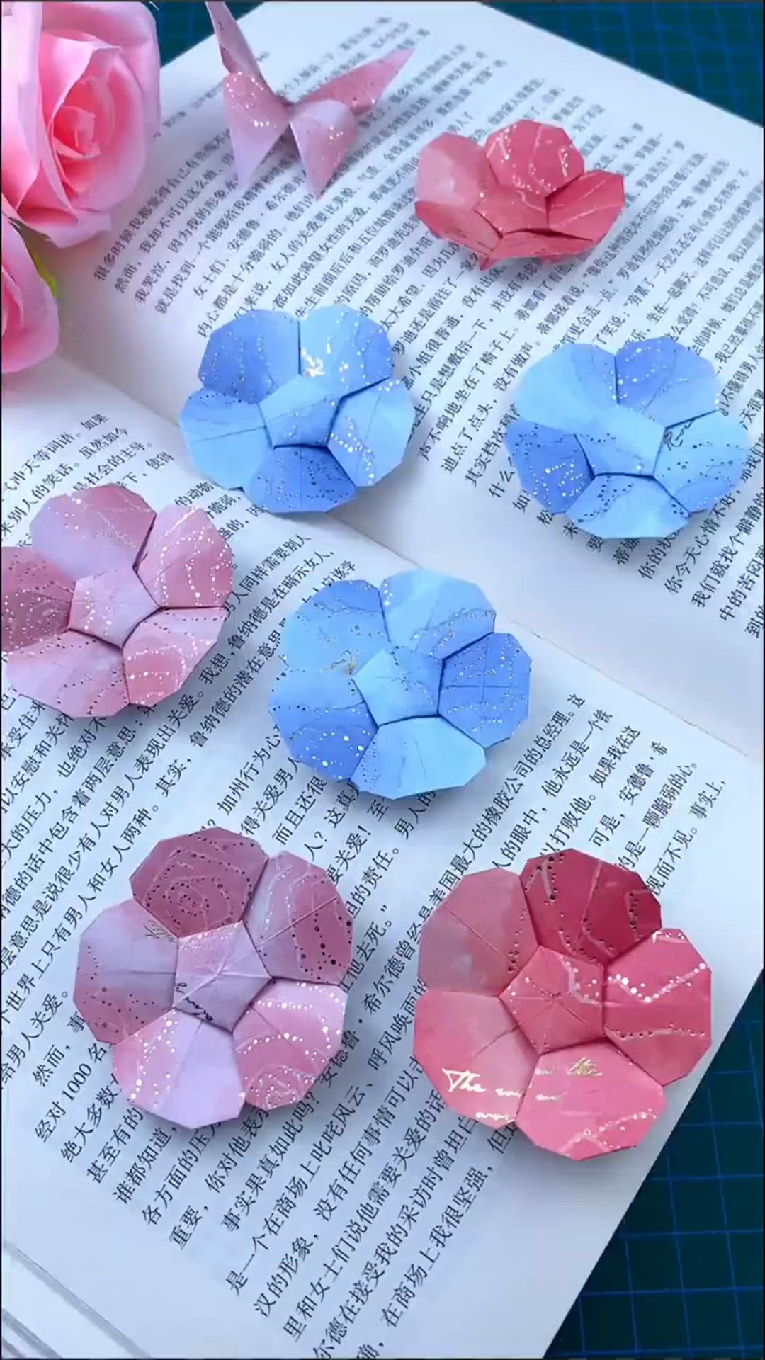 This may contain: four pieces of paper are sitting on top of an open book with pink and blue flowers