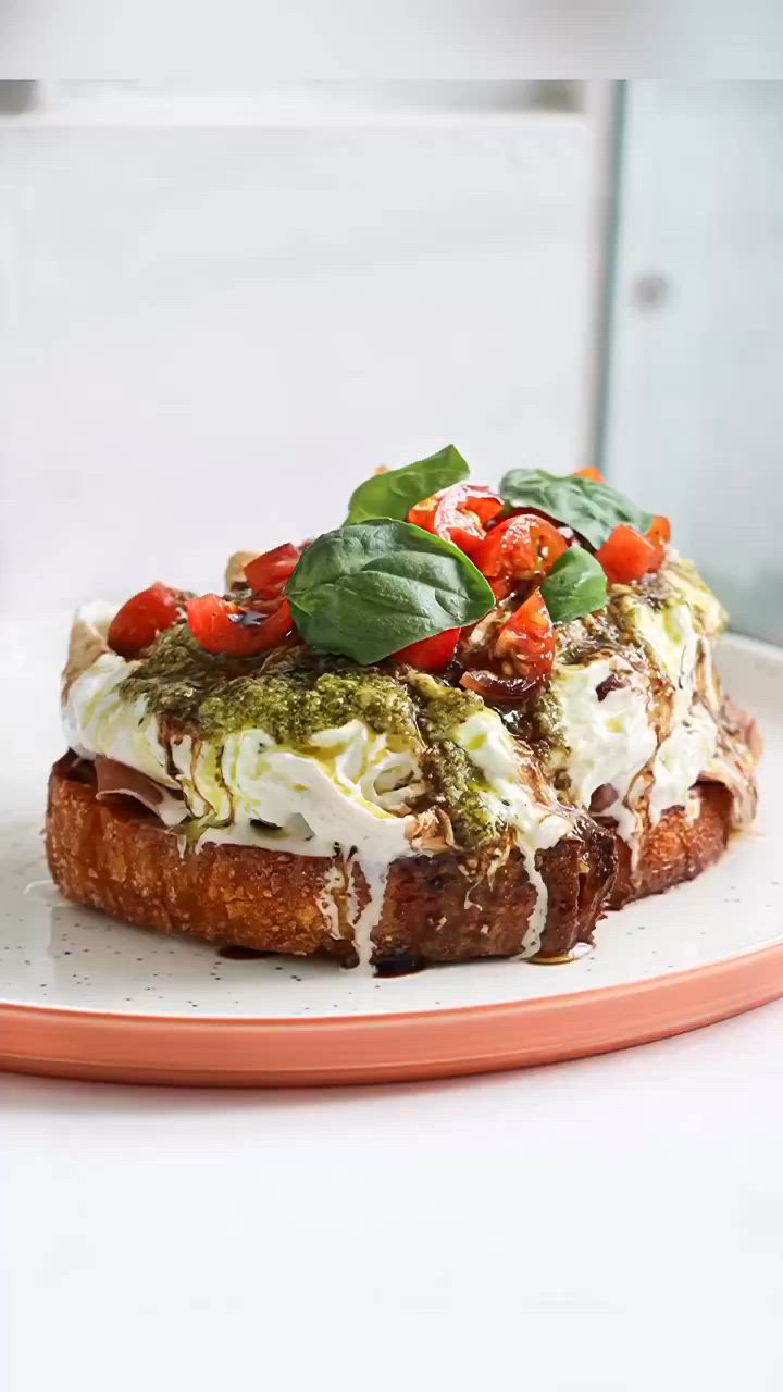 This may contain: a sandwich with tomatoes, mozzarella and pesto on it