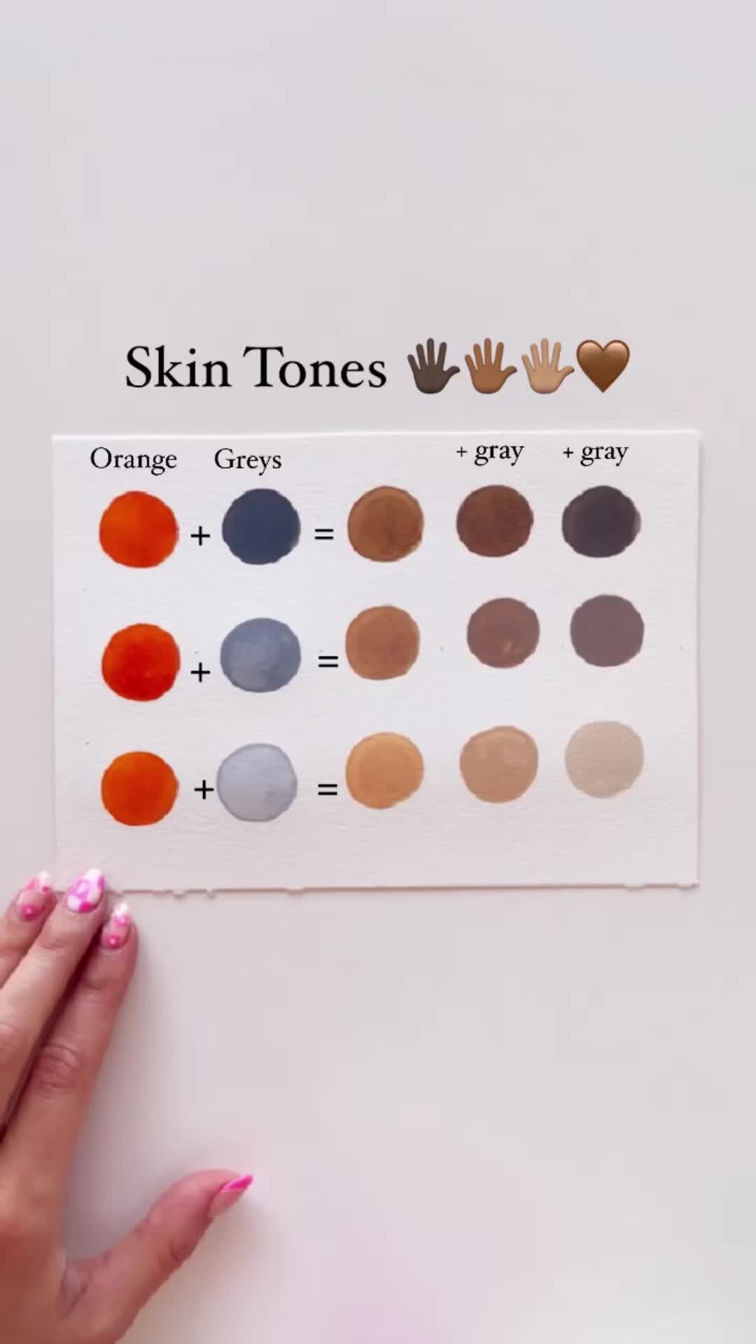 This may contain: a person's hand with pink nail polish holding up a skin tone chart on a white surface