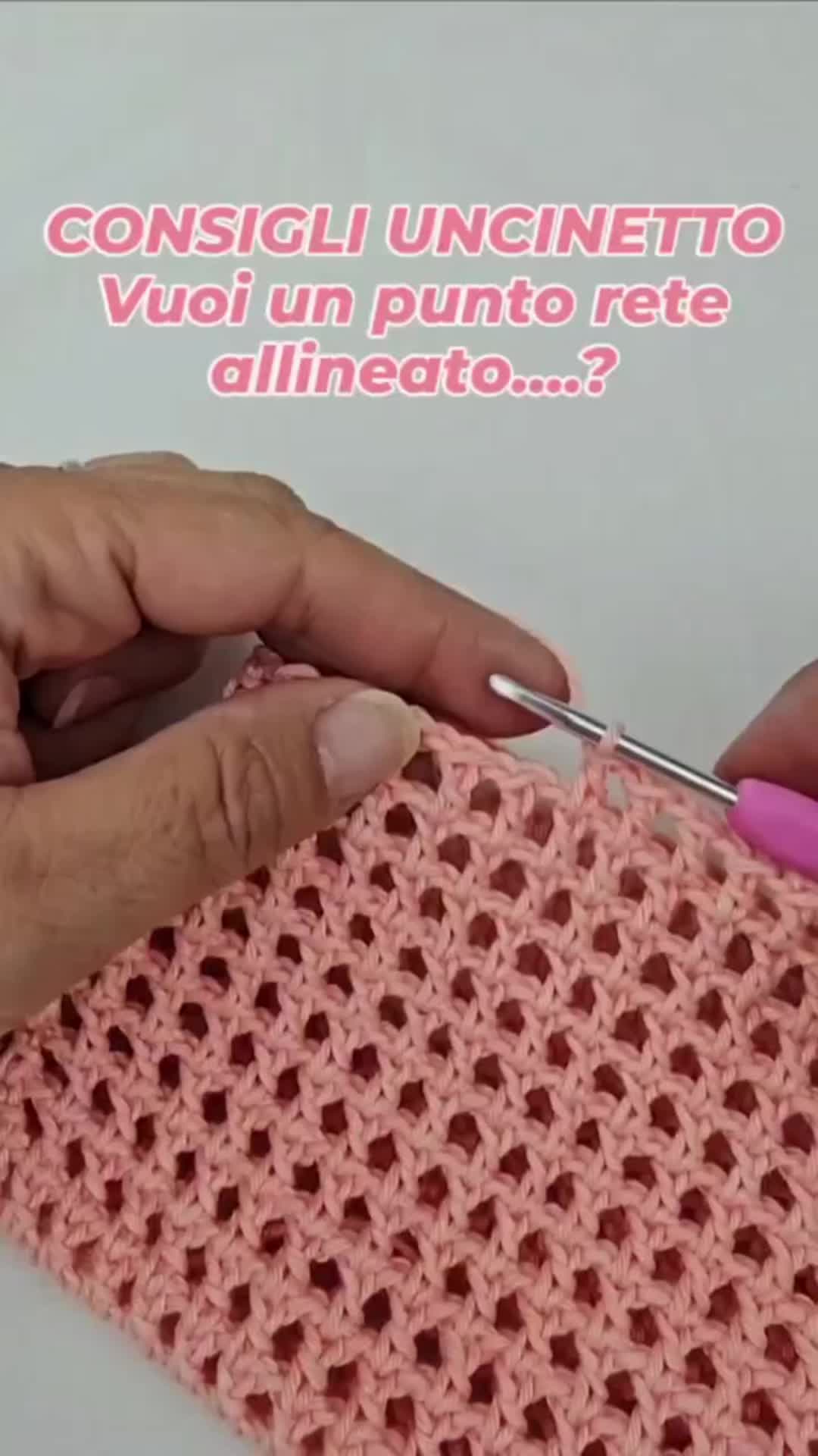 This may contain: two hands crocheting the edges of an afghan with pink yarn, while another hand holds a pair of scissors