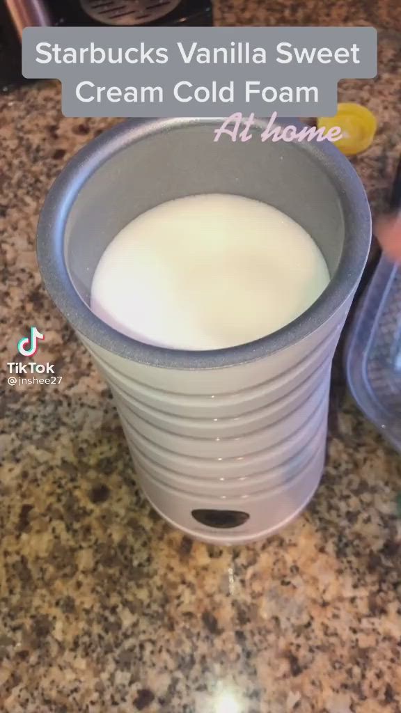 This may contain: a cup filled with milk sitting on top of a counter next to a plastic container