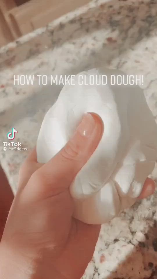 This may contain: a hand holding a doughnut with the words how to make cloud dough on it