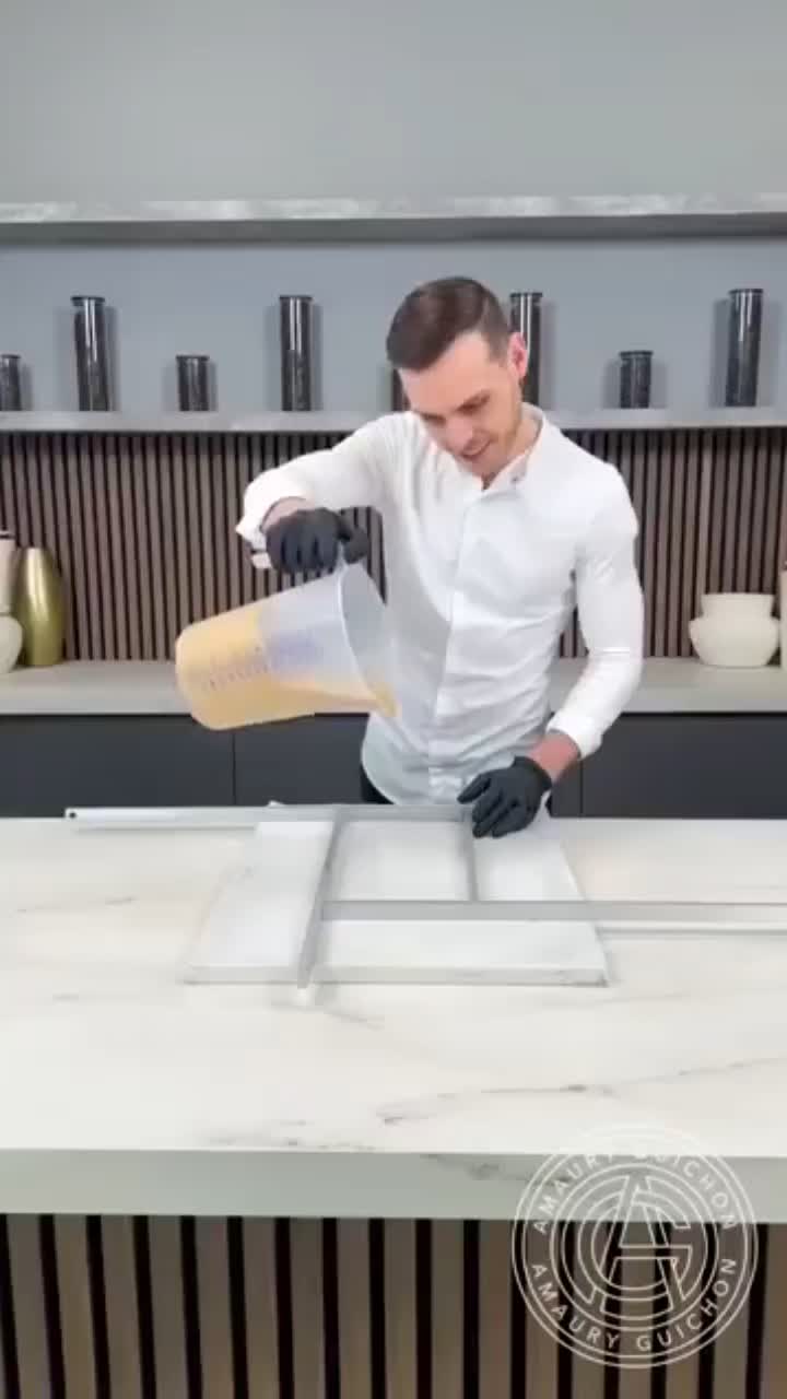 This may contain: a man in white shirt and black gloves standing on top of a counter next to an oven