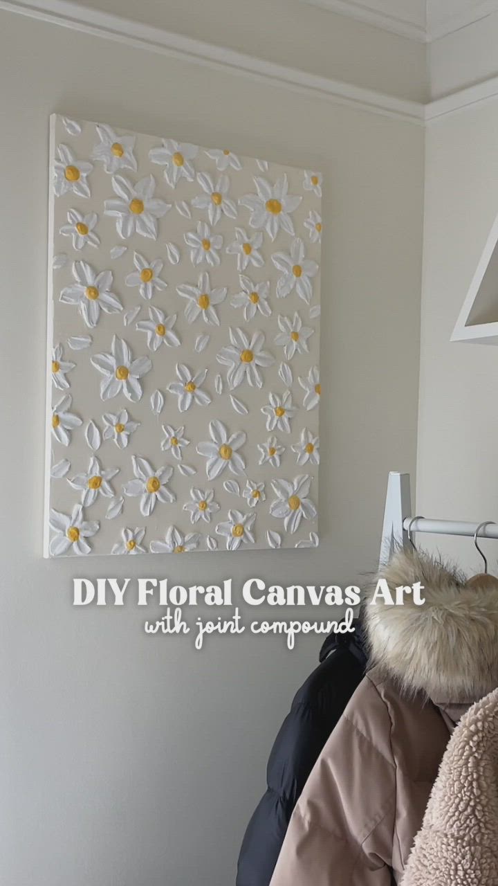 This may contain: a white canvas with yellow daisies on it is hanging in the corner of a room