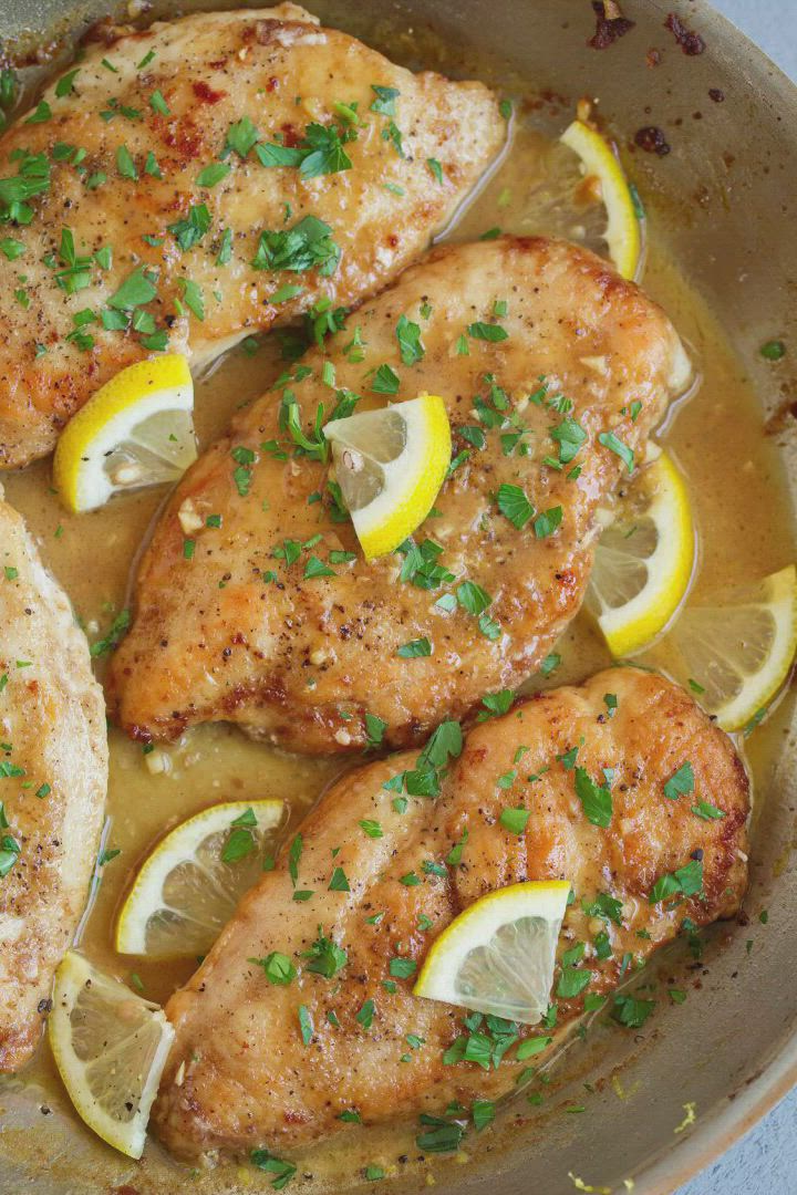 This may contain: chicken with lemons and herbs in a pan