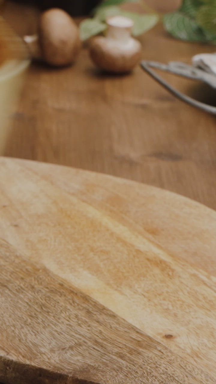 This may contain: a casserole dish with tomatoes and bread on a wooden table next to it