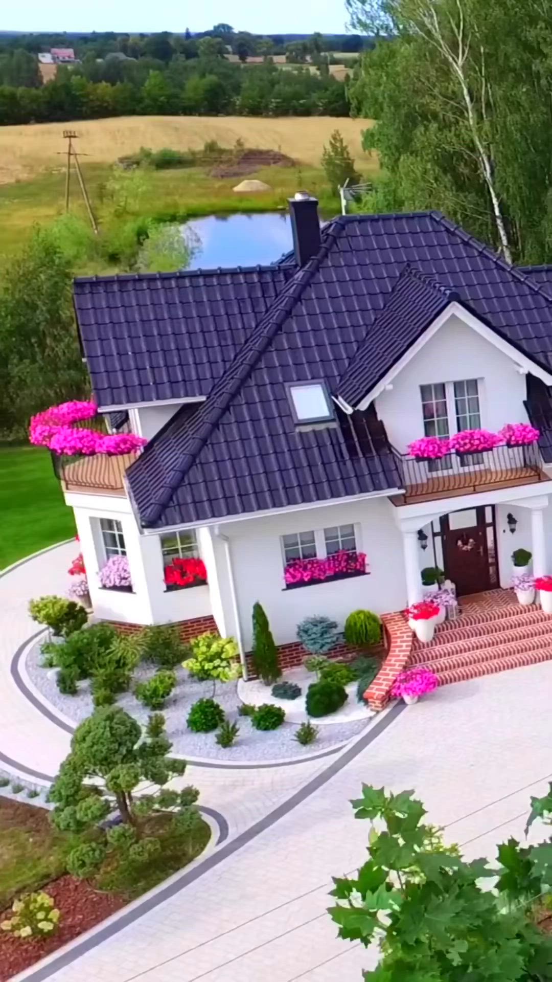 This may contain: an aerial view of a house with flowers in the front yard and landscaping around it