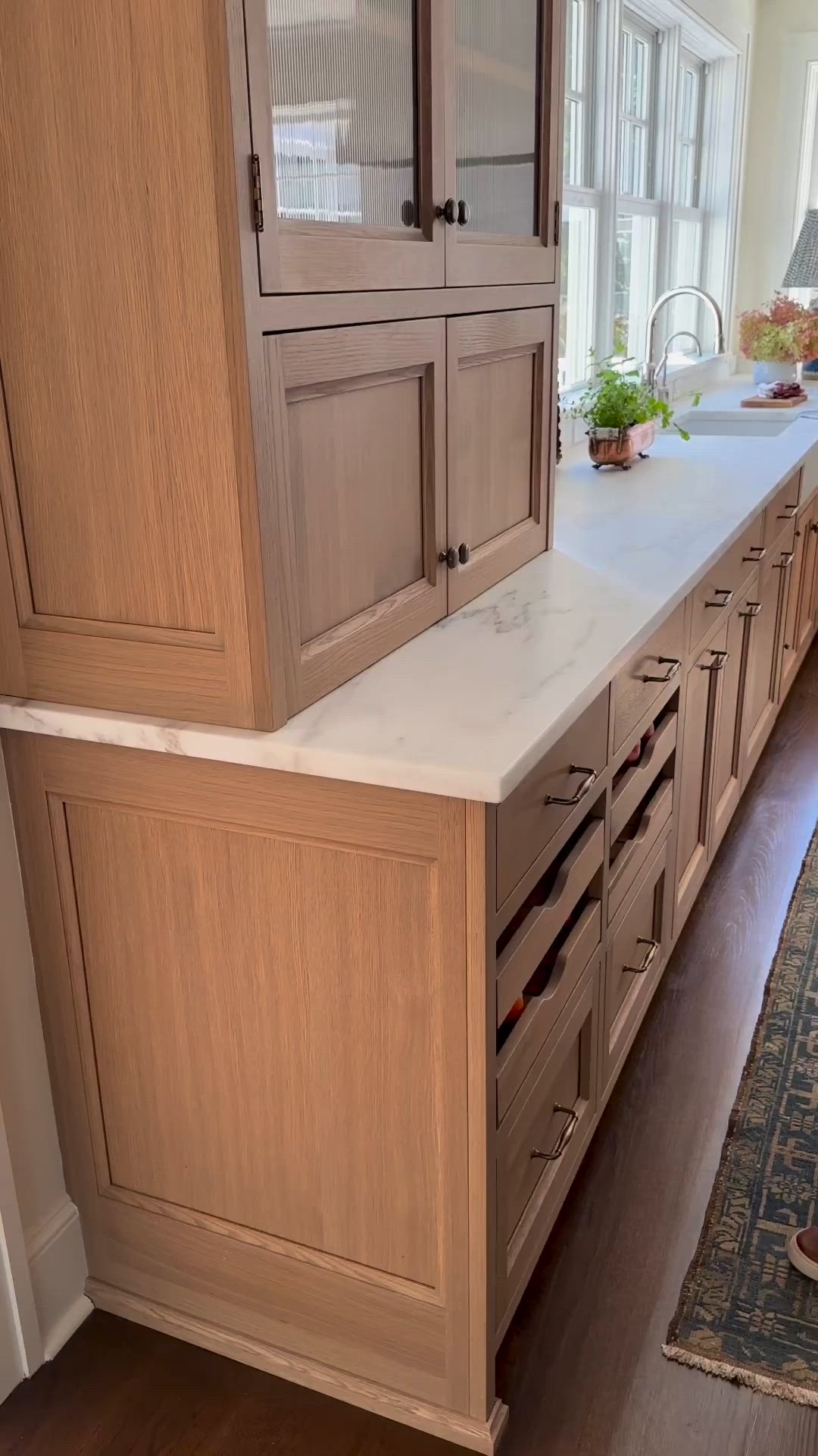 This may contain: a woman standing in front of a wooden cabinet with drawers and doors on the side