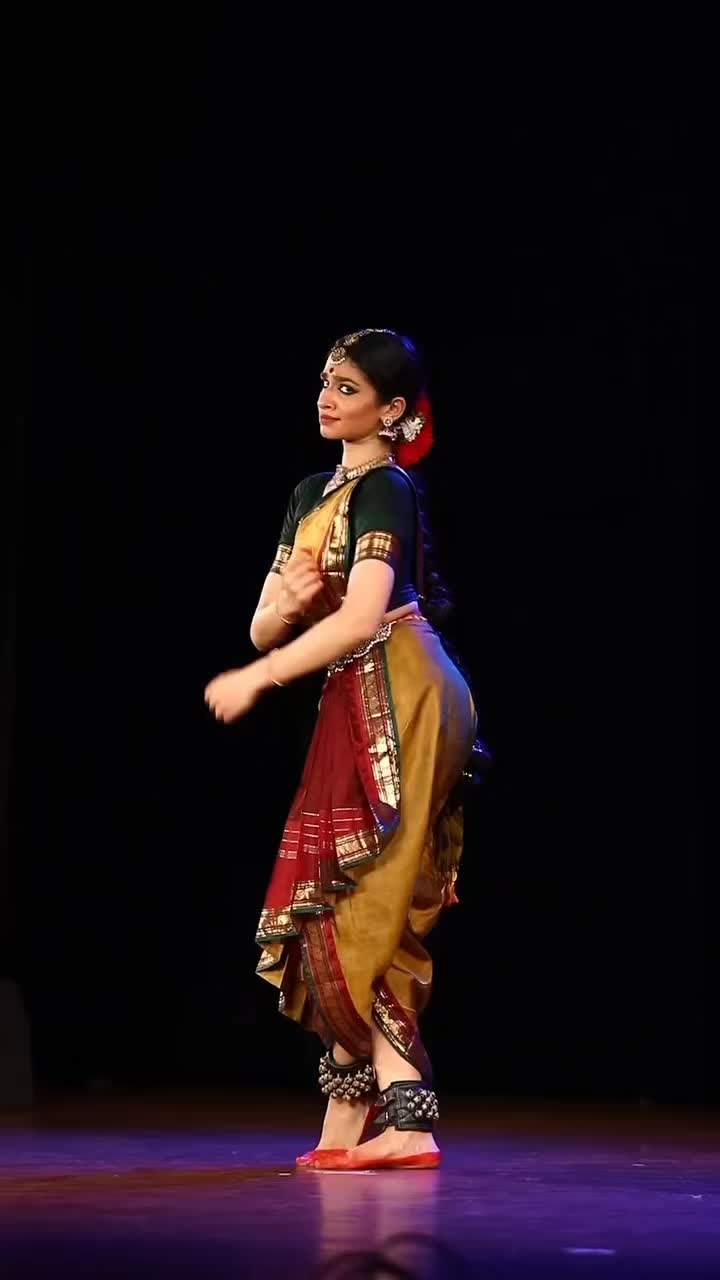 This may contain: a woman in a red and gold dress is dancing on stage with her hands together