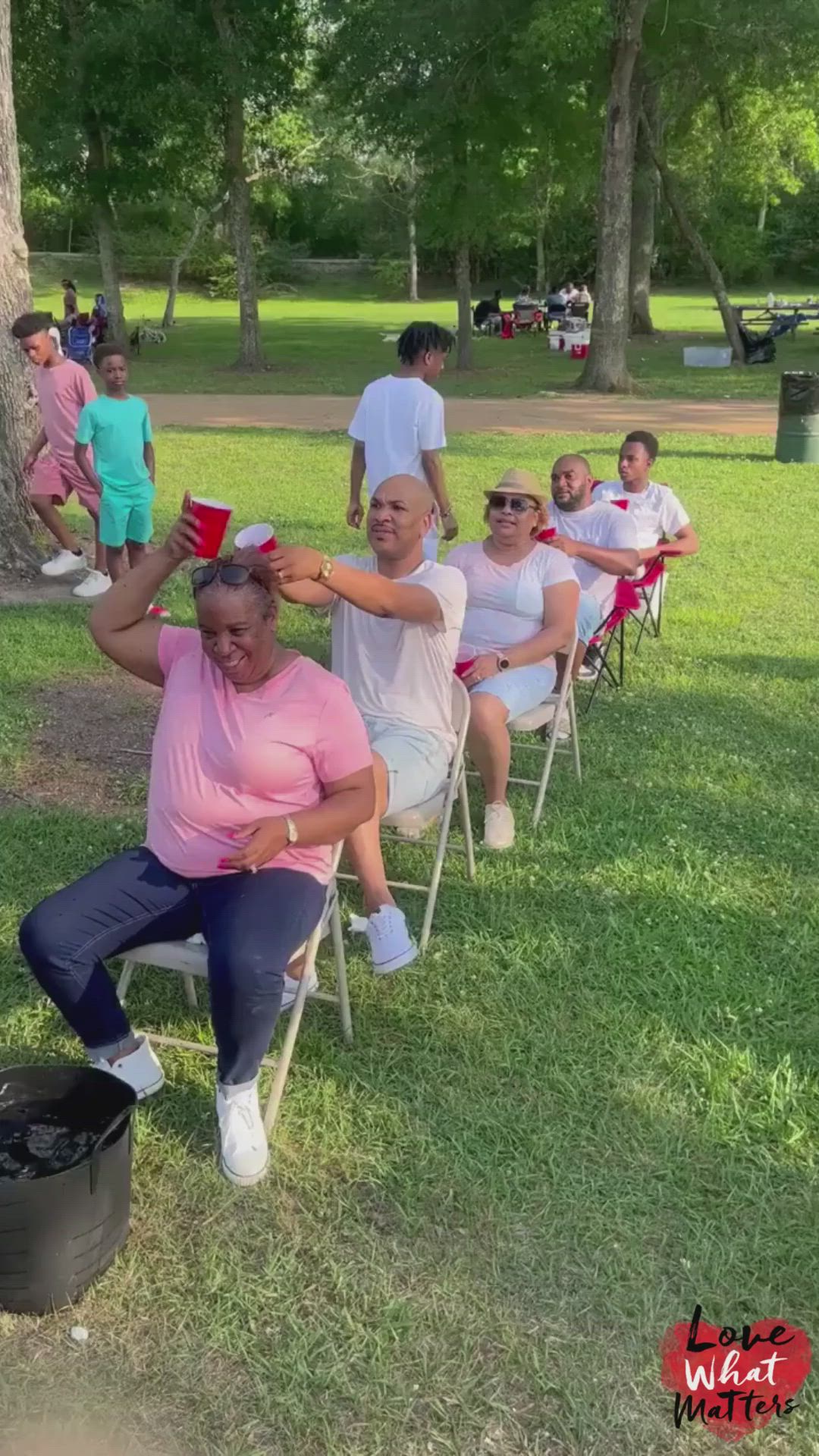 This may contain: people sitting in lawn chairs and one woman is getting her hair brushed by another person