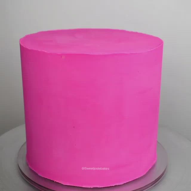 This may contain: a pink cake decorated with green and purple decorations