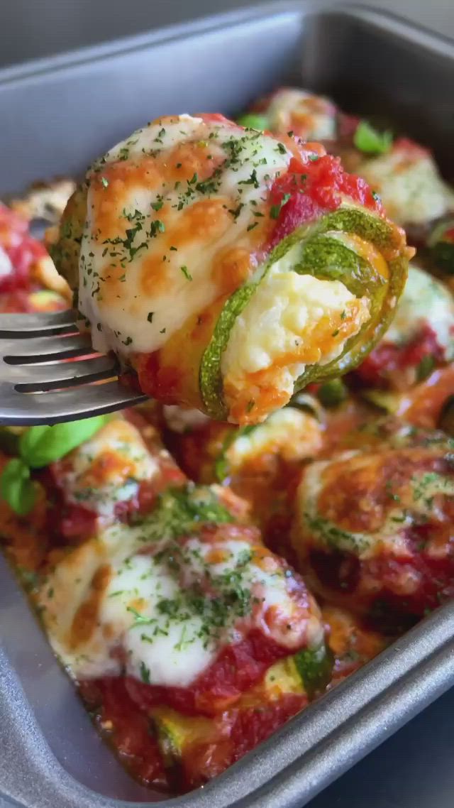 This may contain: a close up of a fork in a casserole dish with cheese and vegetables