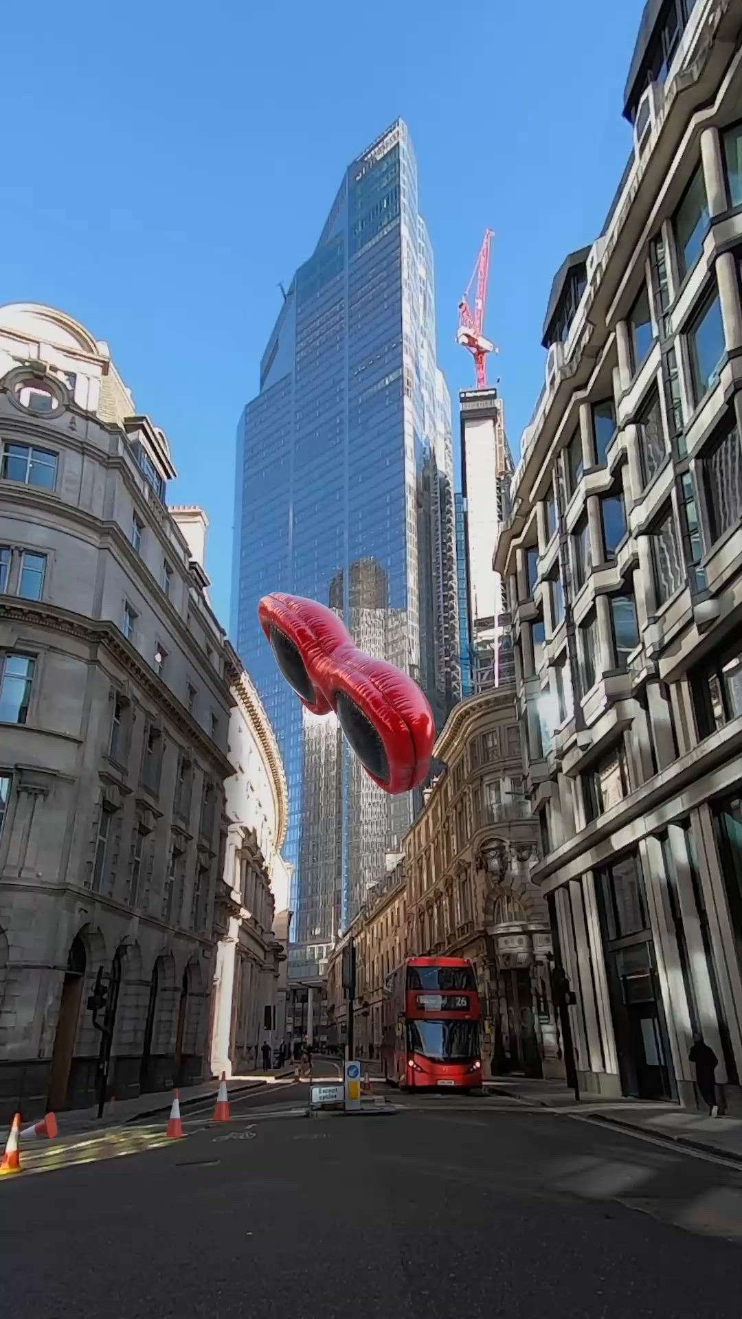 This may contain: a large red object floating in the air between two buildings