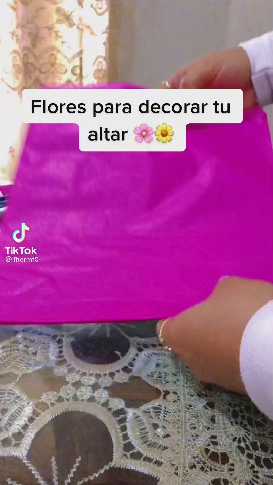 This may contain: a woman is holding a pink bag with flowers on it and the words floress para decora tu altar