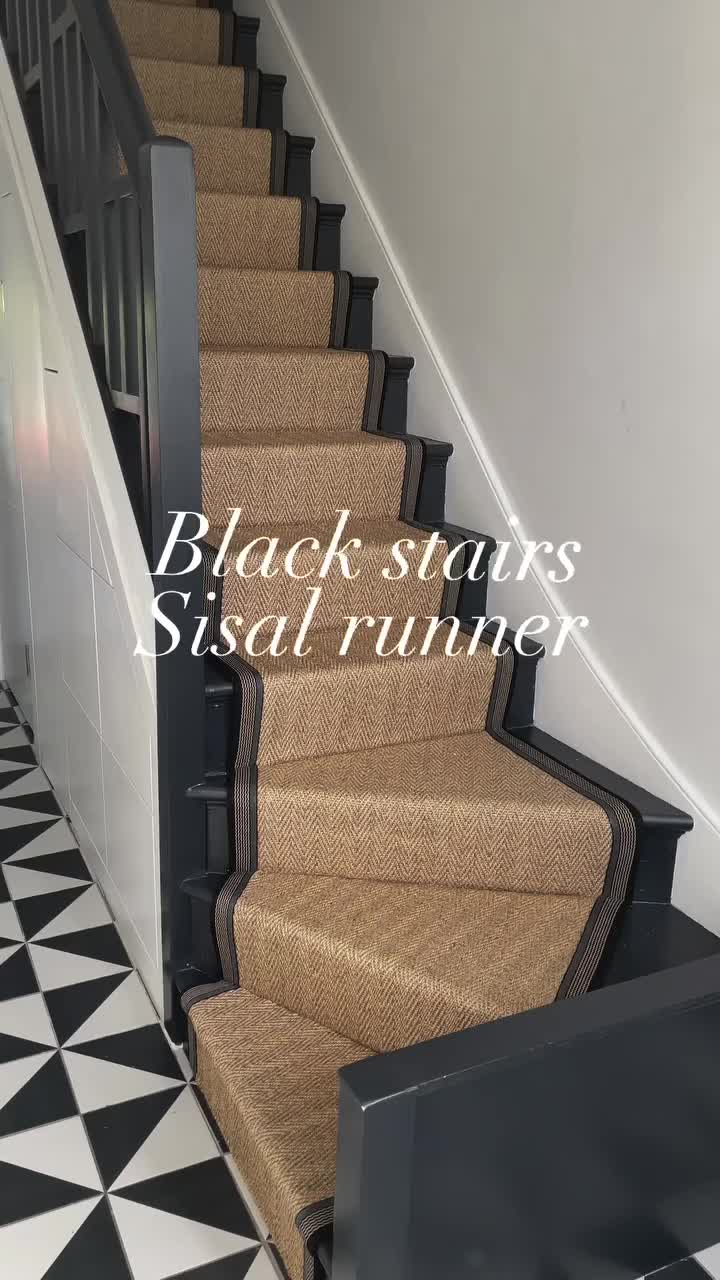 This may contain: an image of a staircase with black stairs and sisal runner on the bottom floor