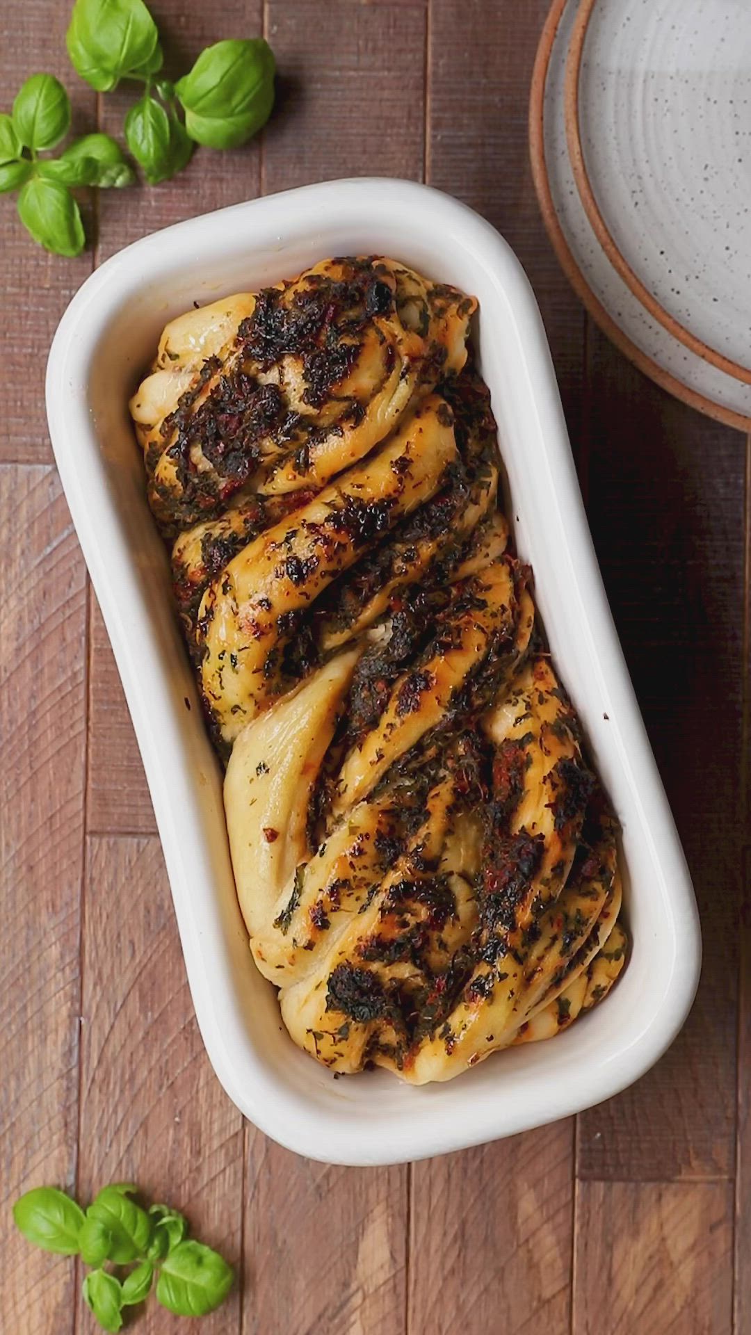 This may contain: spinach tomato bakka in a white casserole dish on a wooden table