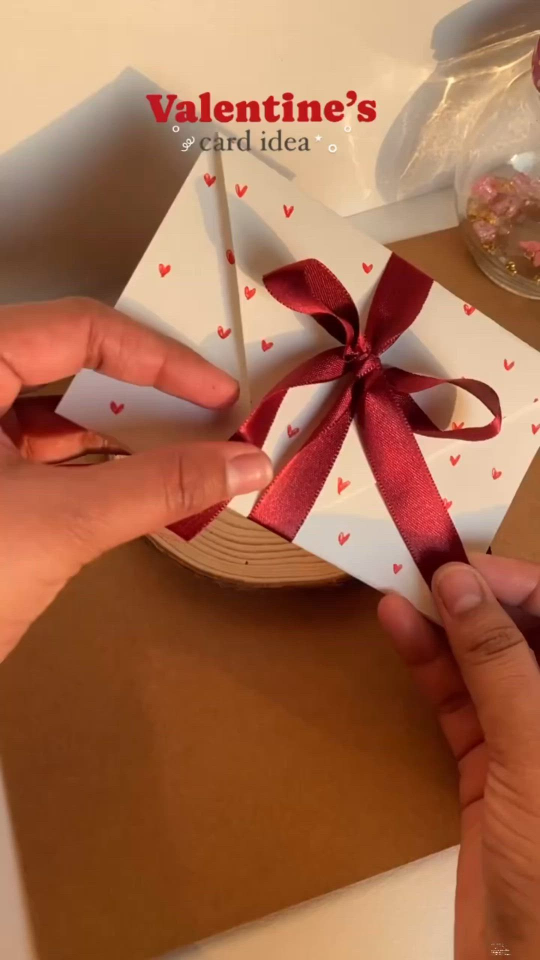 This may contain: someone cutting out a valentine's card with a red bow on the front and side