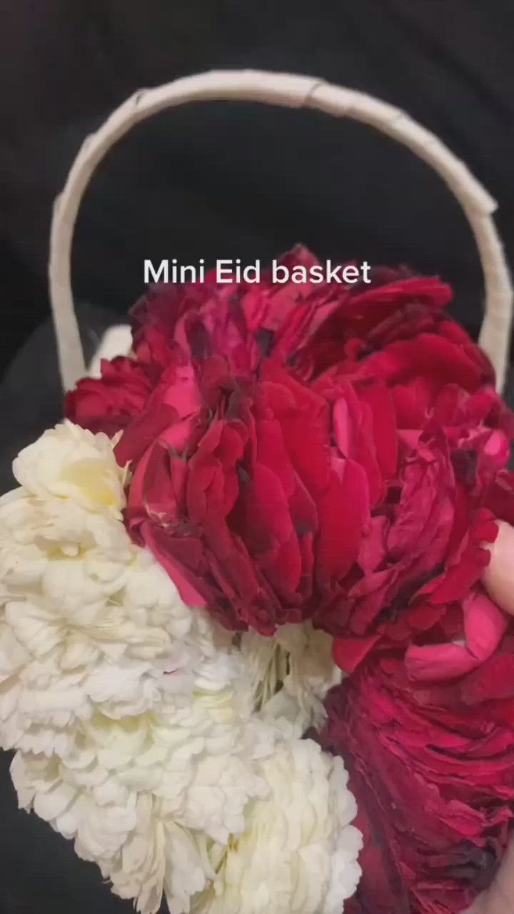 This may contain: a person holding a basket with flowers in it and the words mini eld basket above it