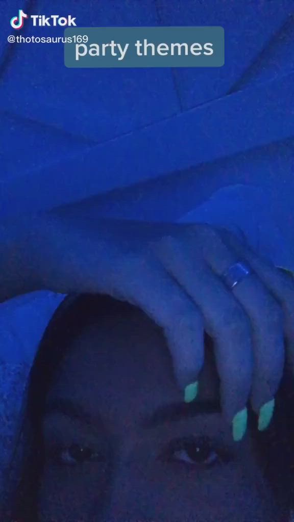 This may contain: a woman with green nails covering her face in the dark, under a blue blanket