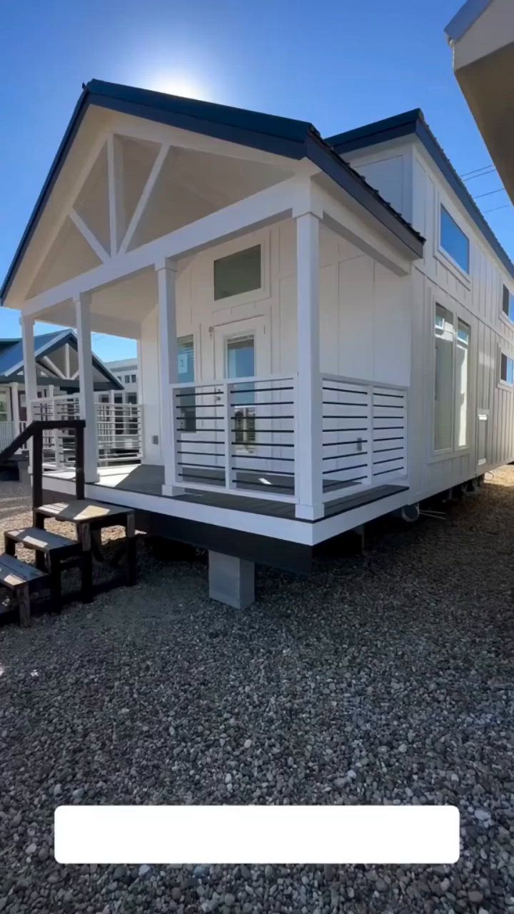 This may contain: a mobile home sits on the gravel with stairs leading up to it's roof