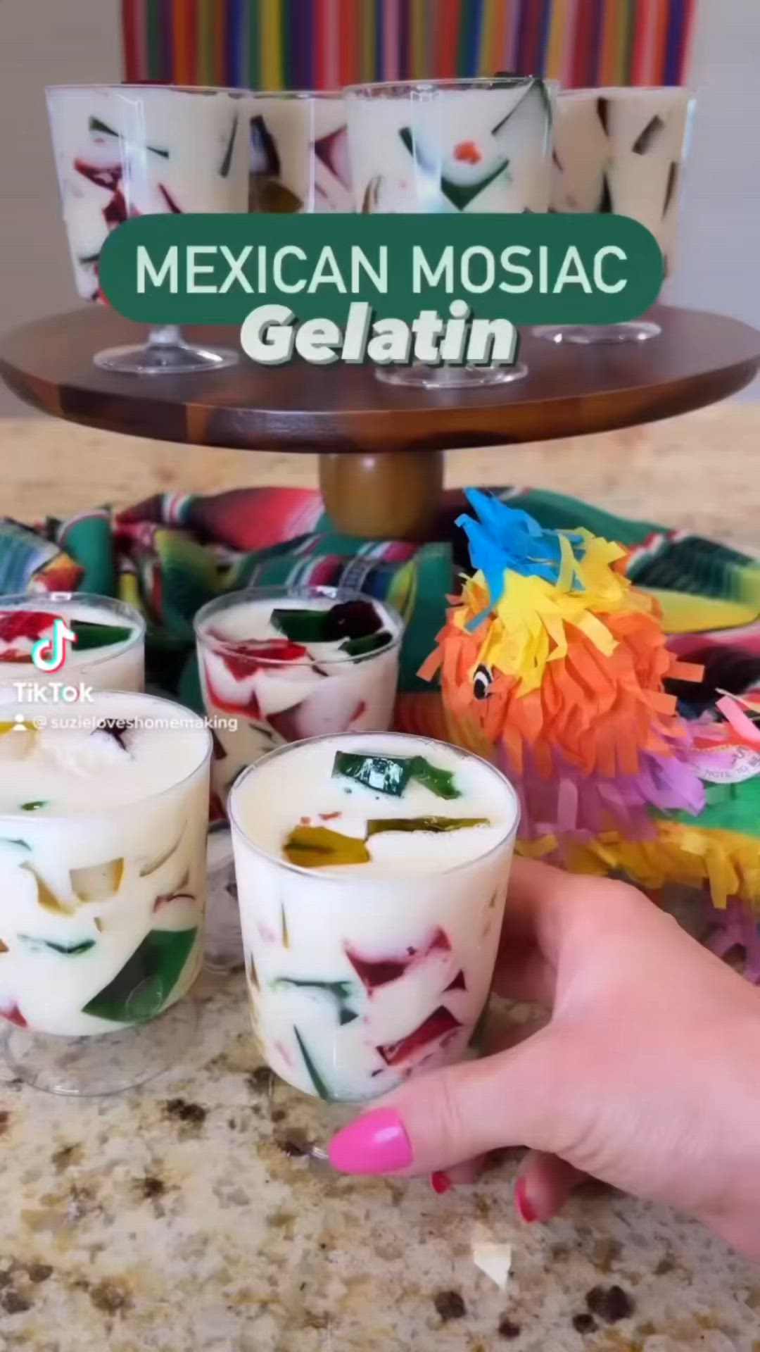 This may contain: a person is holding a candle in front of other candles on a counter top with mexican mosaic gelatin