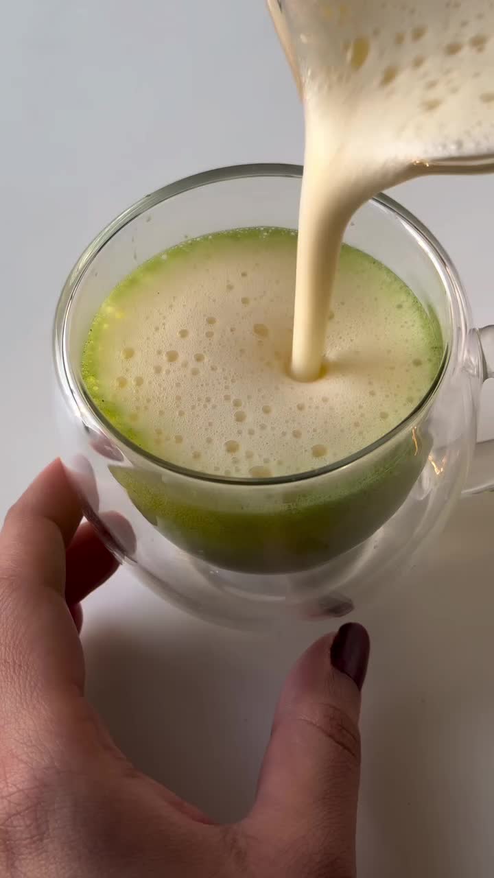 This may contain: a person is pouring something into a glass with the words matcha egg nog