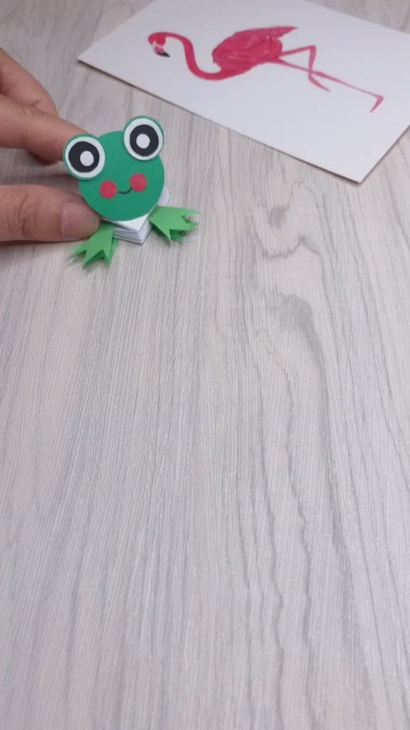 This may contain: someone is making a paper frog craft on the table