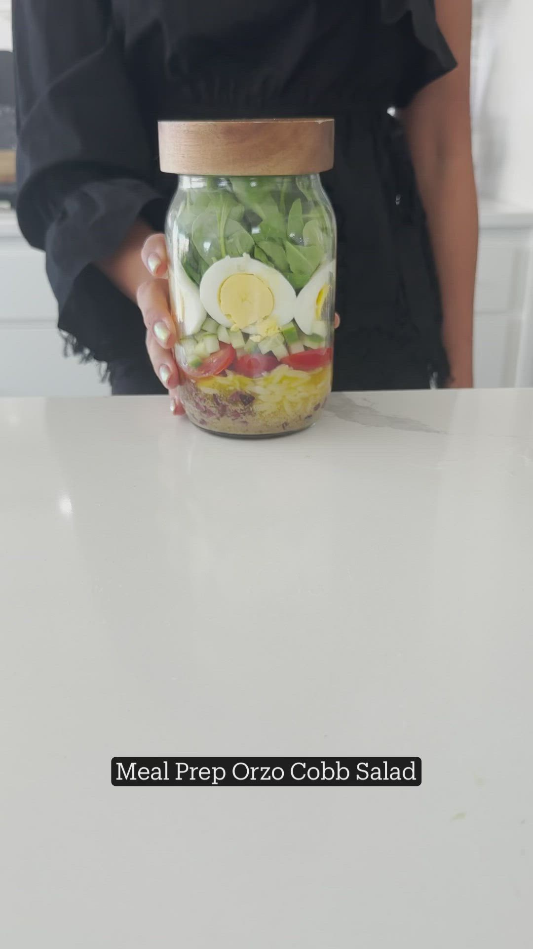 This may contain: a person holding a mason jar filled with vegetables and eggs on top of a white counter