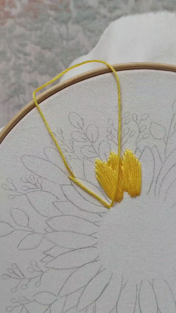 This may contain: a close up of a flower embroidery on a white piece of cloth with yellow thread