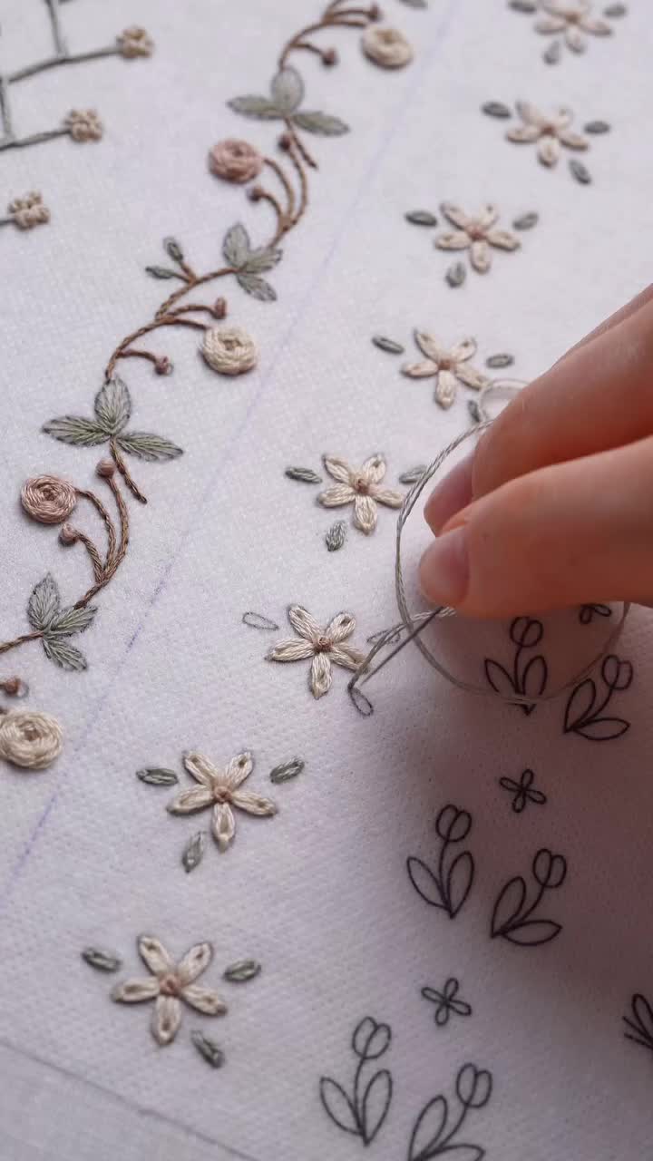 This may contain: someone is stitching flowers on a piece of fabric