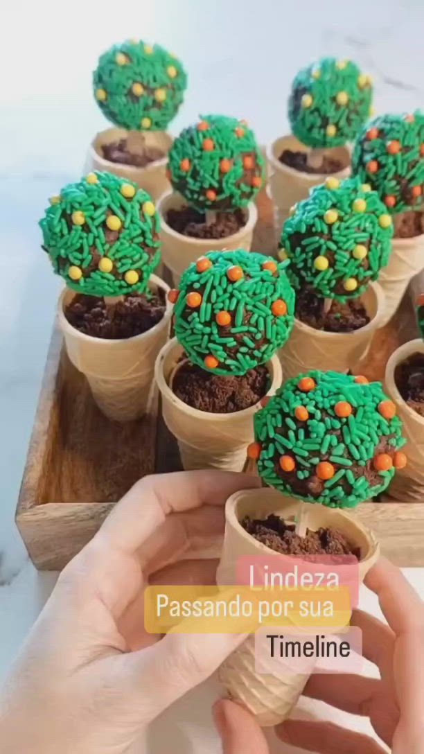 This may contain: someone is holding a cupcake in front of some small cactus plants on a tray