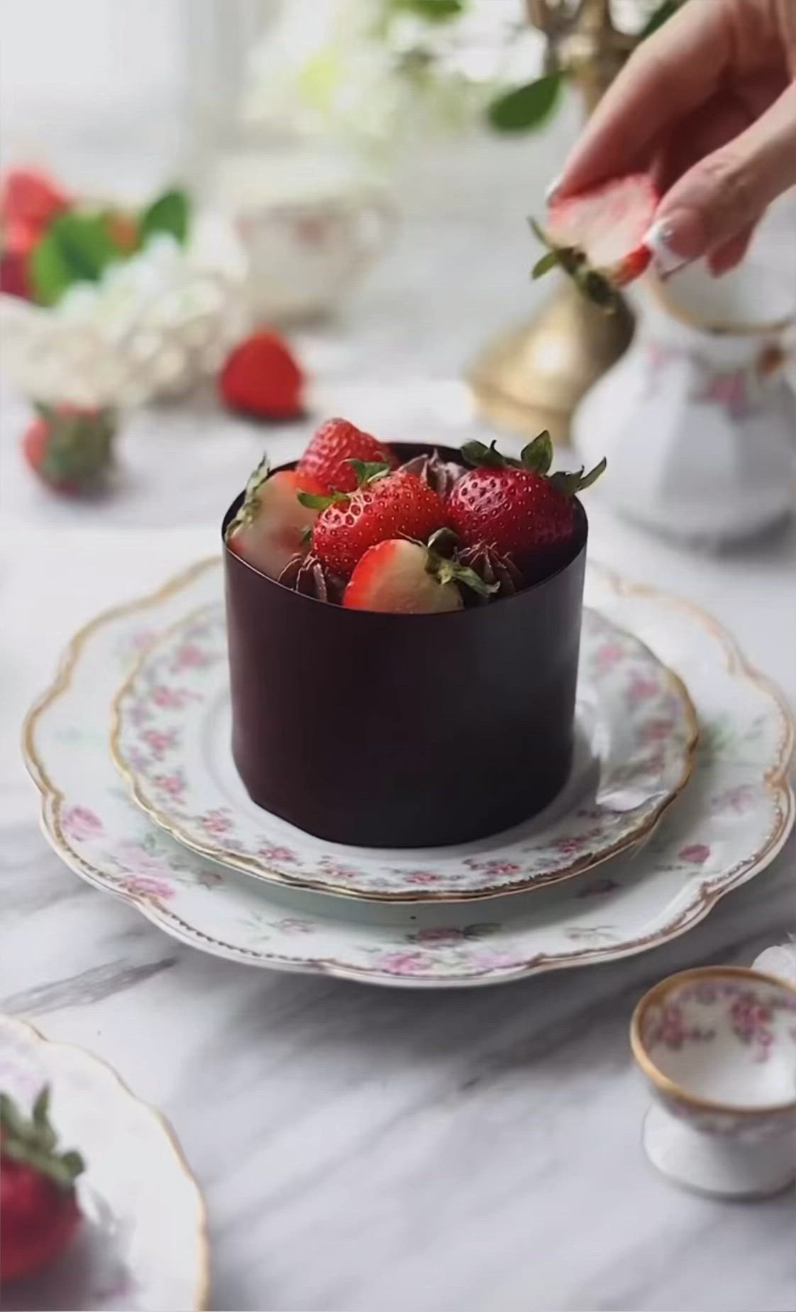 This may contain: a person is picking strawberries from a bowl on a table with other plates and cups