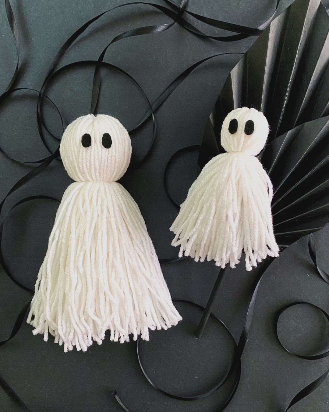 This may contain: two white yarn tassels sitting on top of each other with the words easy halloween craft how to make yarn ghosts