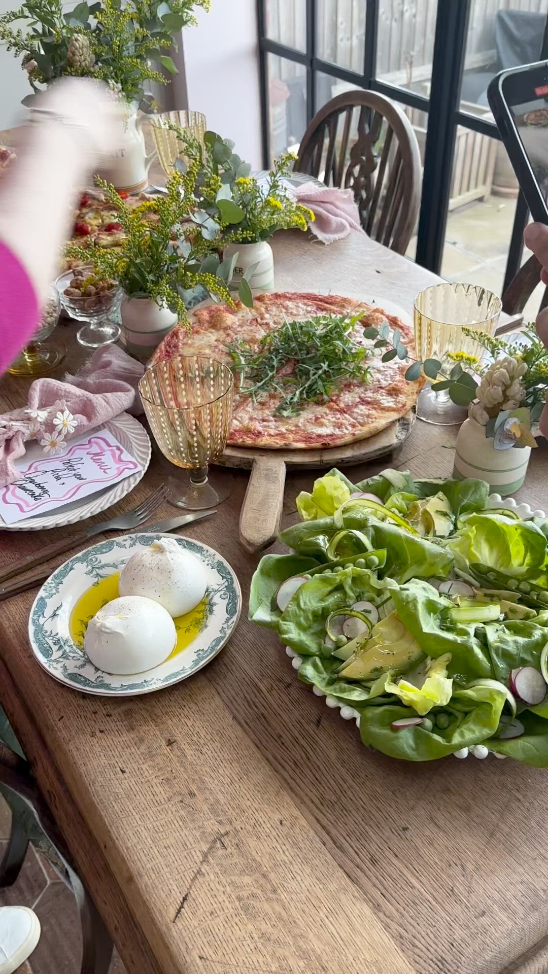 This may contain: a wooden table topped with lots of plates and bowls filled with food on top of it