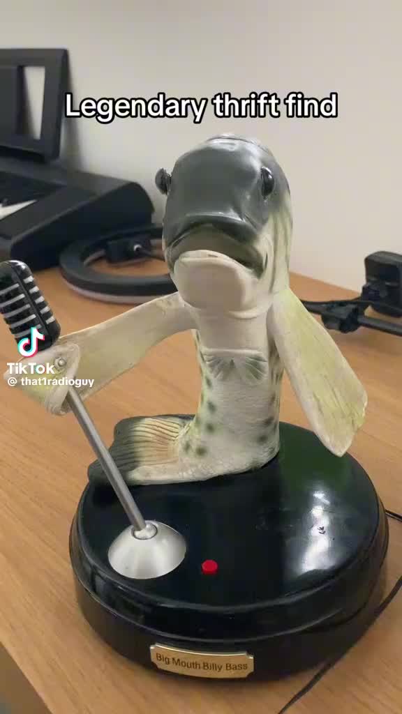 This may contain: a statue of a fish is on top of a desk with a toothbrush in it's mouth