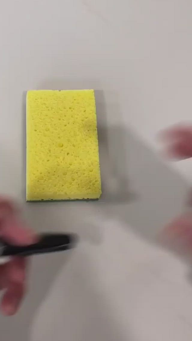 This may contain: someone is using a pair of scissors to clean a piece of yellow paper on the wall