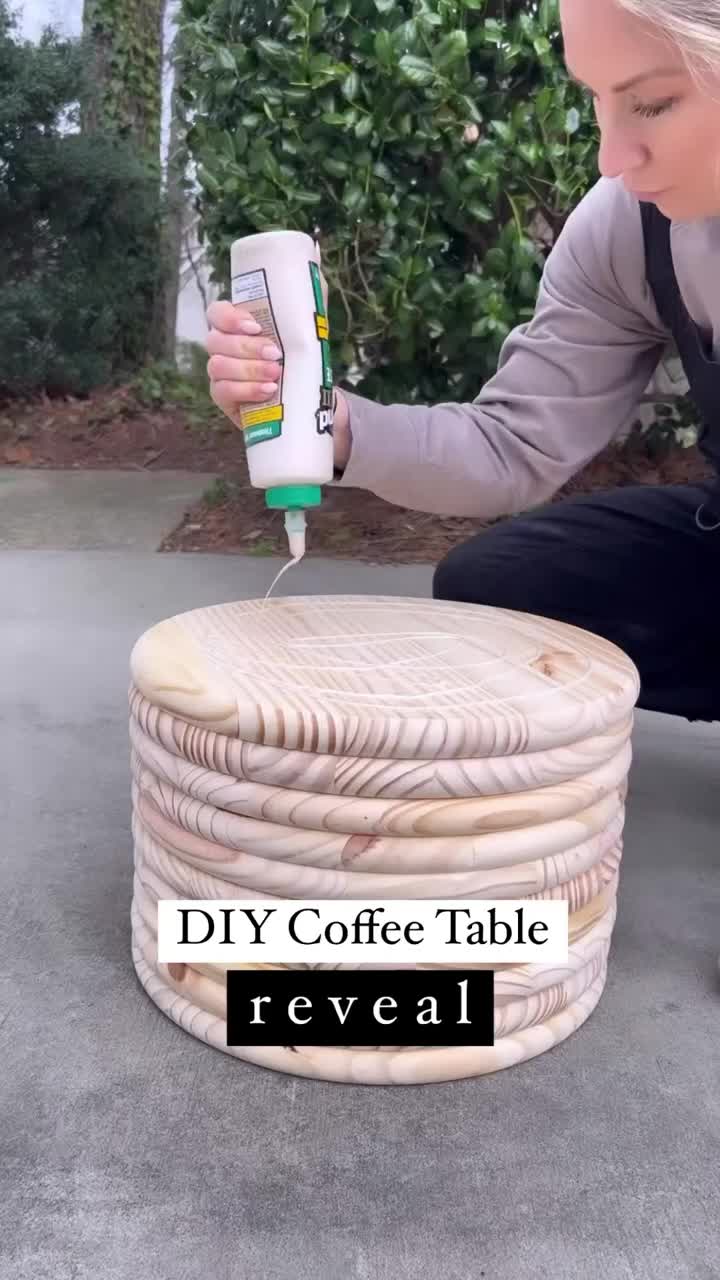 This may contain: a woman kneeling down with a coffee table made out of wicker and paint rollers