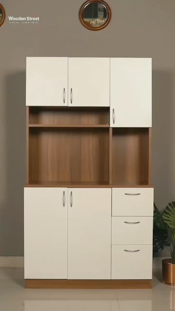 This may contain: a white cabinet with wooden doors and drawers next to a potted plant on the floor