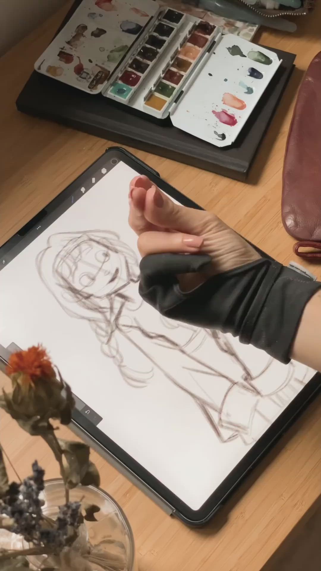 This may contain: a person is drawing on a tabletop next to a vase with flowers in it