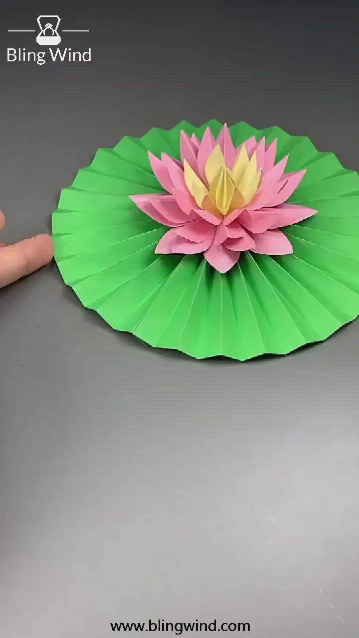 This may contain: a paper lotus flower sitting on top of a green leaf next to a blue marker