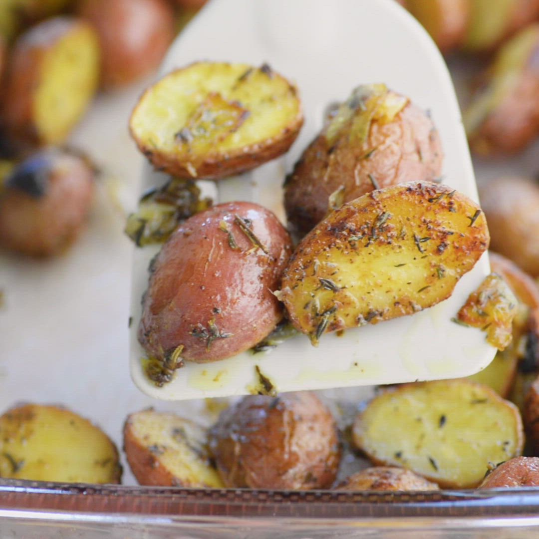 This may contain: a person holding a bowl full of potatoes with seasoning on them and a spoon in it