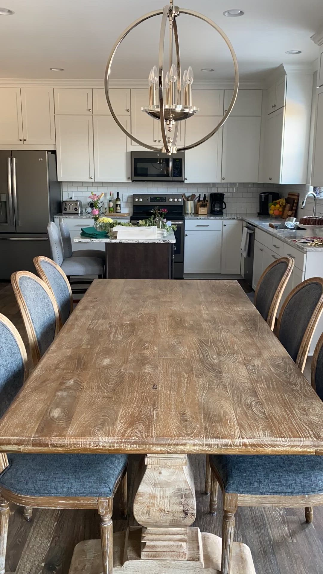 This may contain: a wooden table surrounded by blue chairs in a kitchen