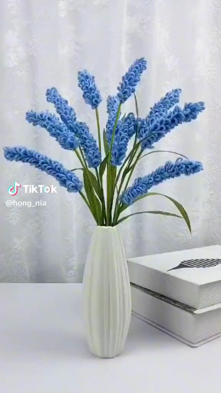 This may contain: a white vase filled with blue flowers next to a box