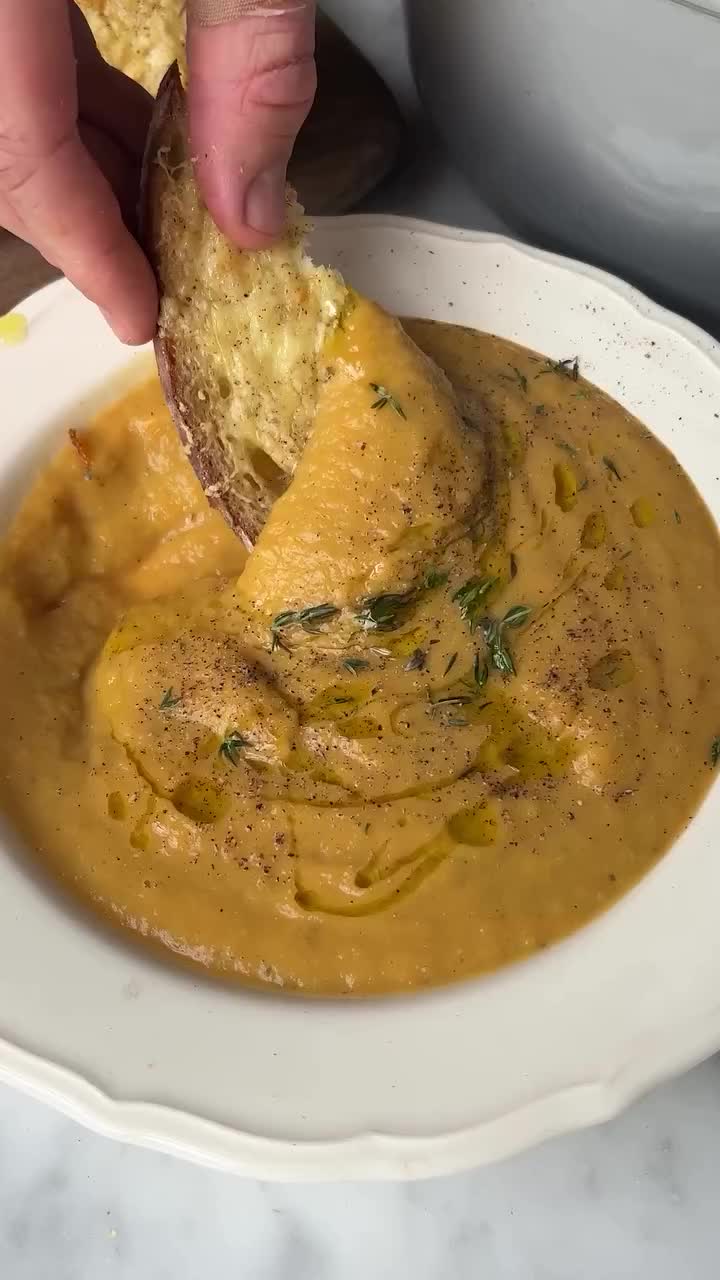 This may contain: a person dipping some bread into a bowl of soup