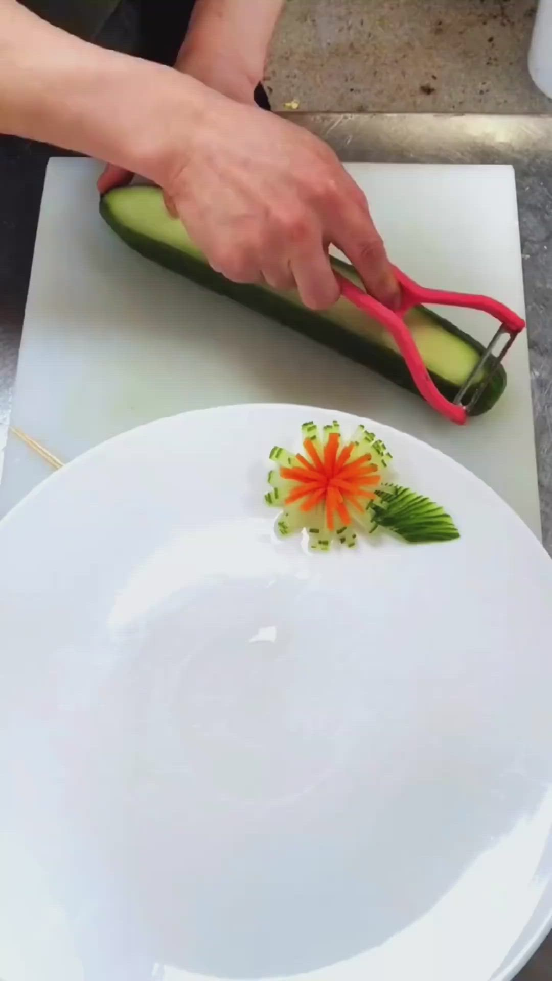 This may contain: a person cutting up a cucumber on a white plate with a flower decoration