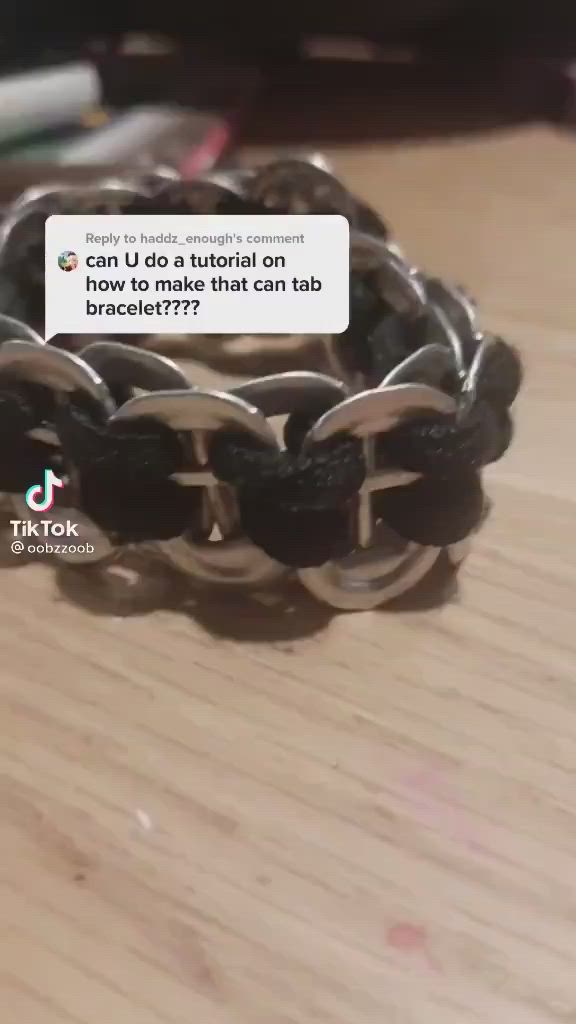 This may contain: a close up of a bracelet on a wooden table with a cell phone in the background