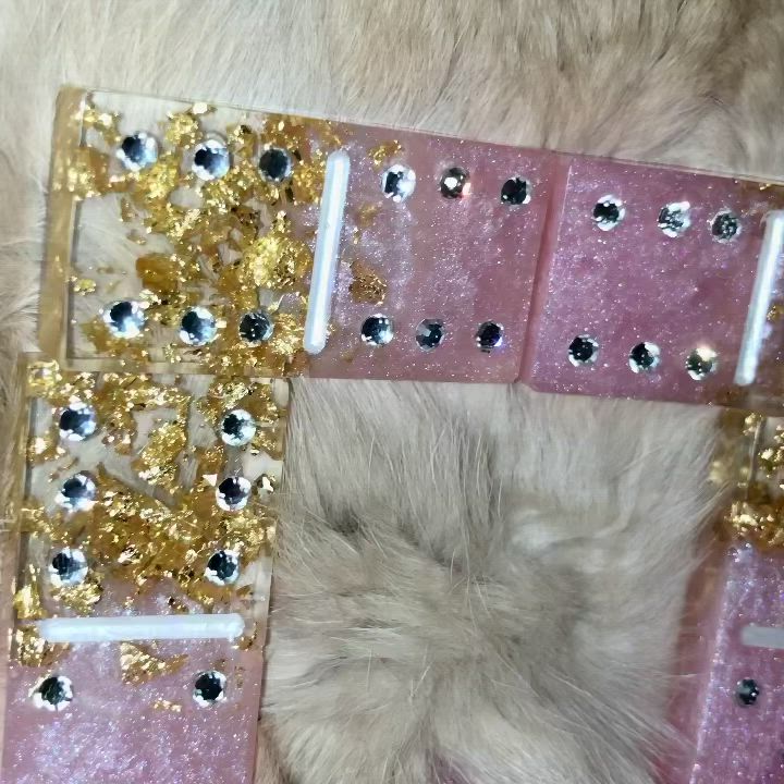 This may contain: a cat laying on top of a pink and gold case with lots of sequins