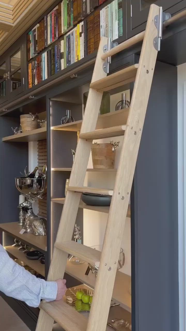 This may contain: a man standing next to a ladder in front of a book shelf filled with books