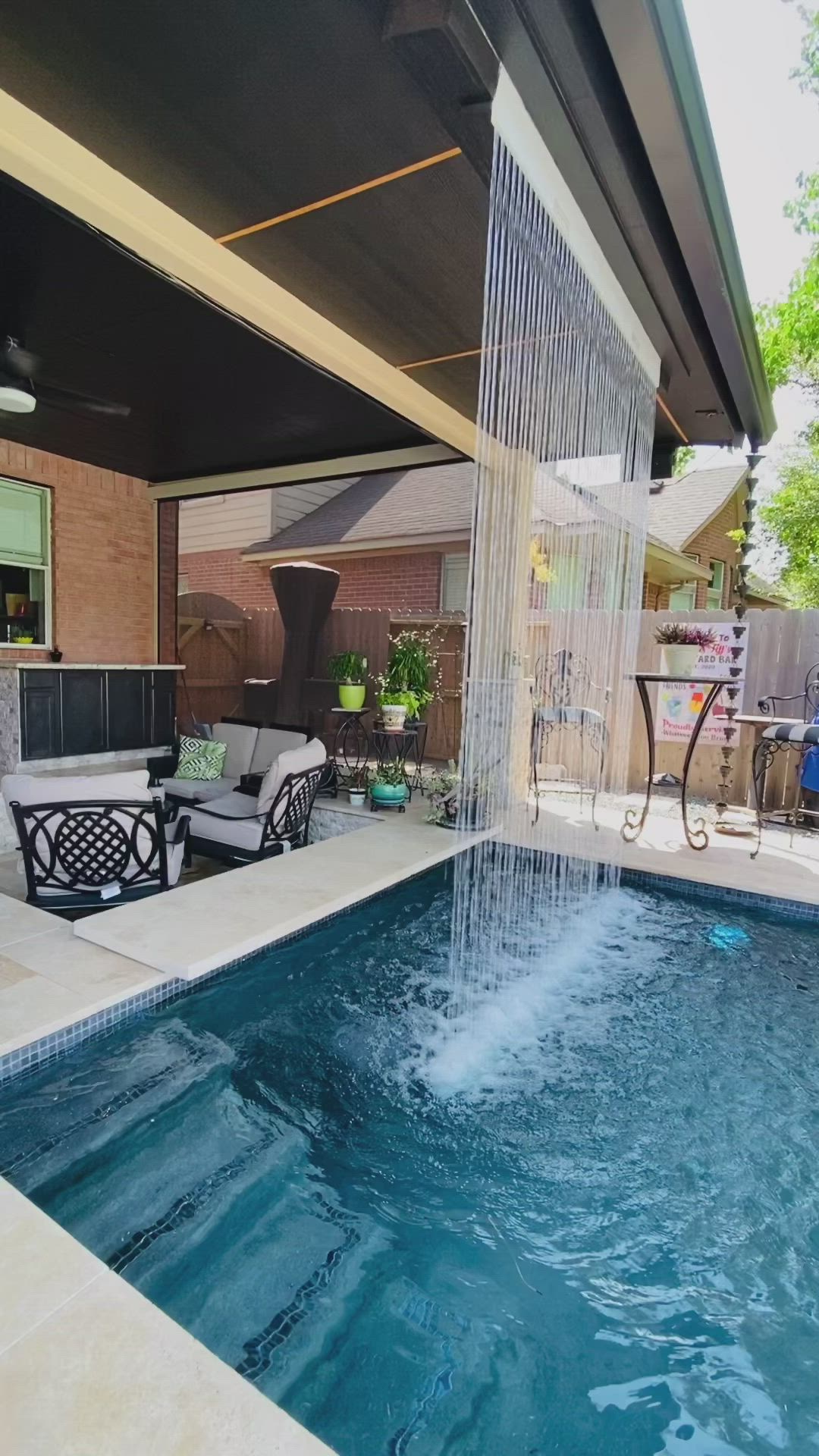 This may contain: a backyard with a pool, patio furniture and an outdoor shower head in the middle