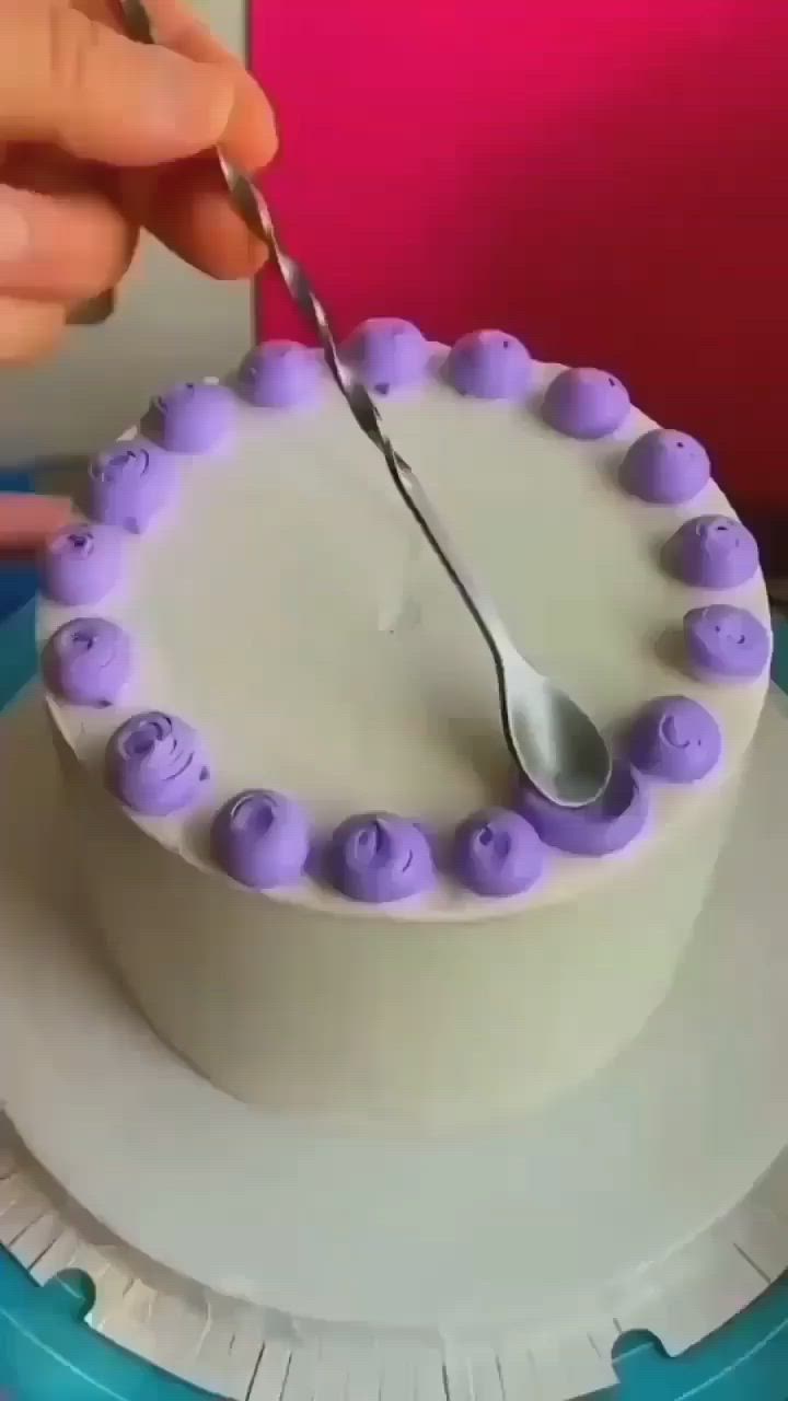 This may contain: a person is cutting into a cake with purple icing on the top and bottom